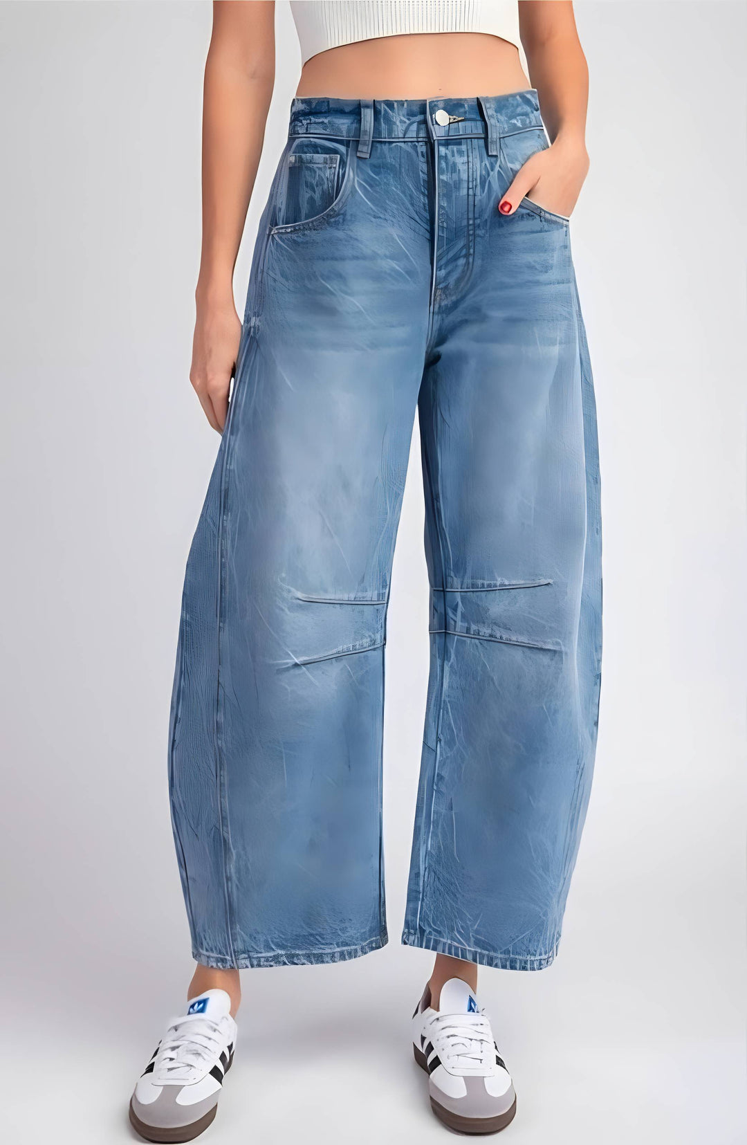 A person wearing light blue wide-leg cropped denim jeans with front patch pockets, paired with white sneakers against a light gray studio background.