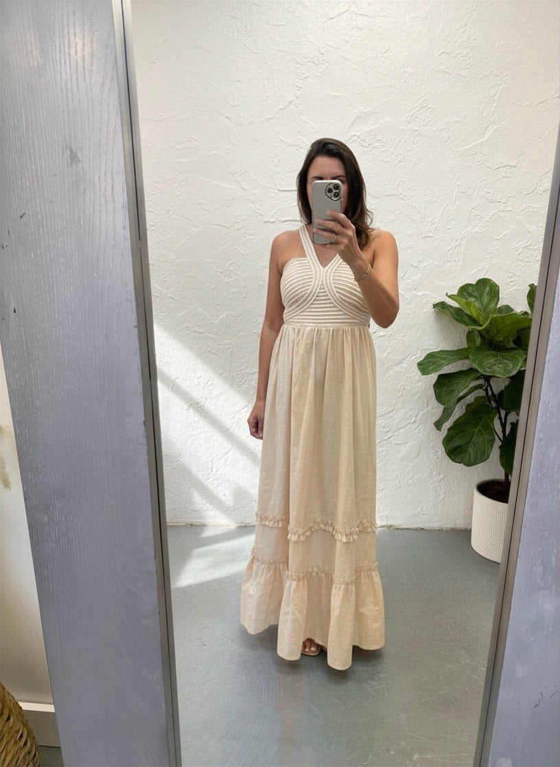 Woman wearing a beige halter neck dress standing in front of a mirror.