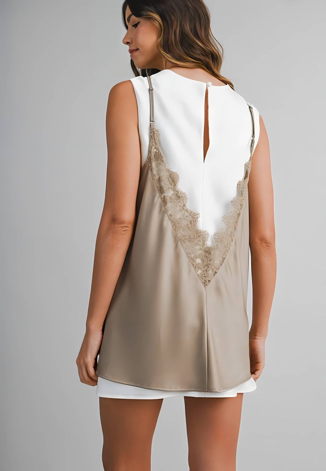 Woman wearing a sleeveless top with lace detailing on a gray background