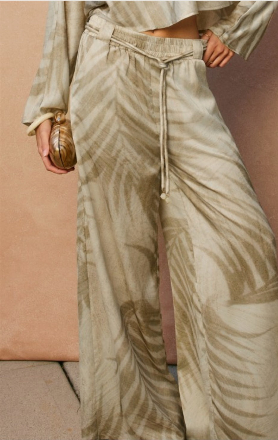Person wearing beige patterned pants with a plain background