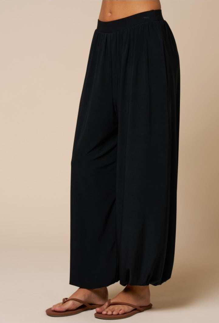 Black wide-leg pants worn by a person on a beige background