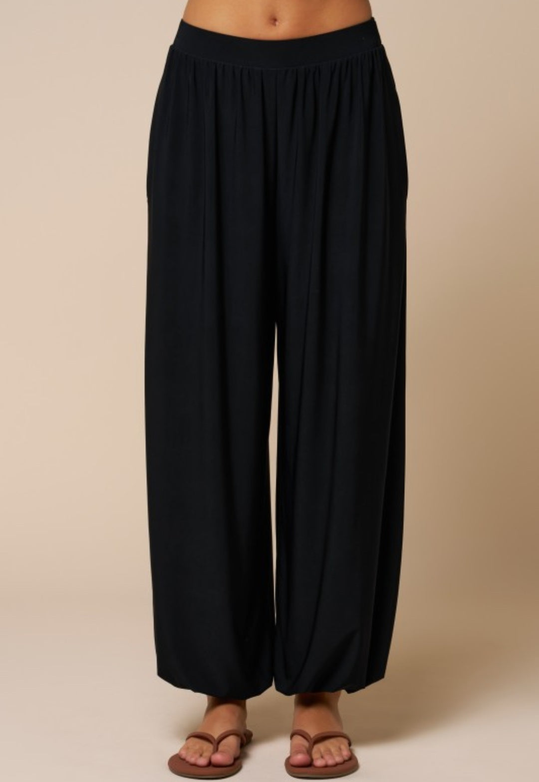 Black wide-leg pants worn by a person on a beige background