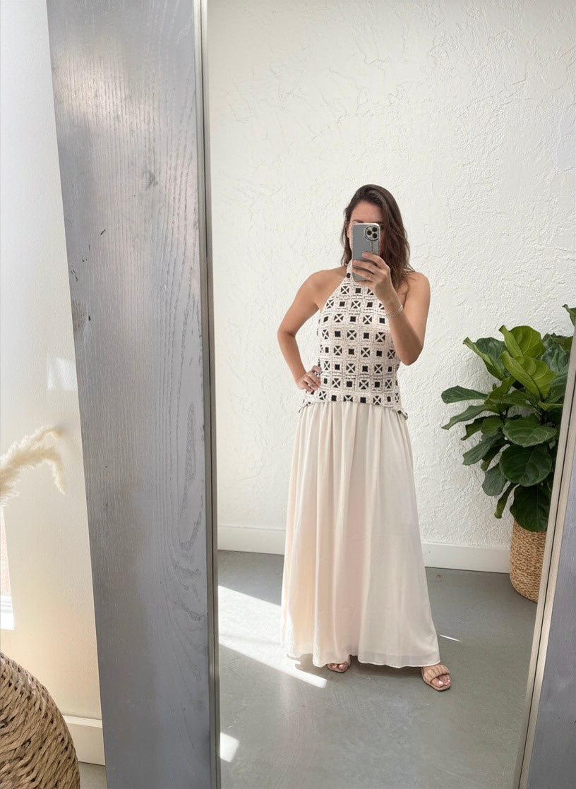 Woman taking a mirror selfie wearing a white dress with black patterns.