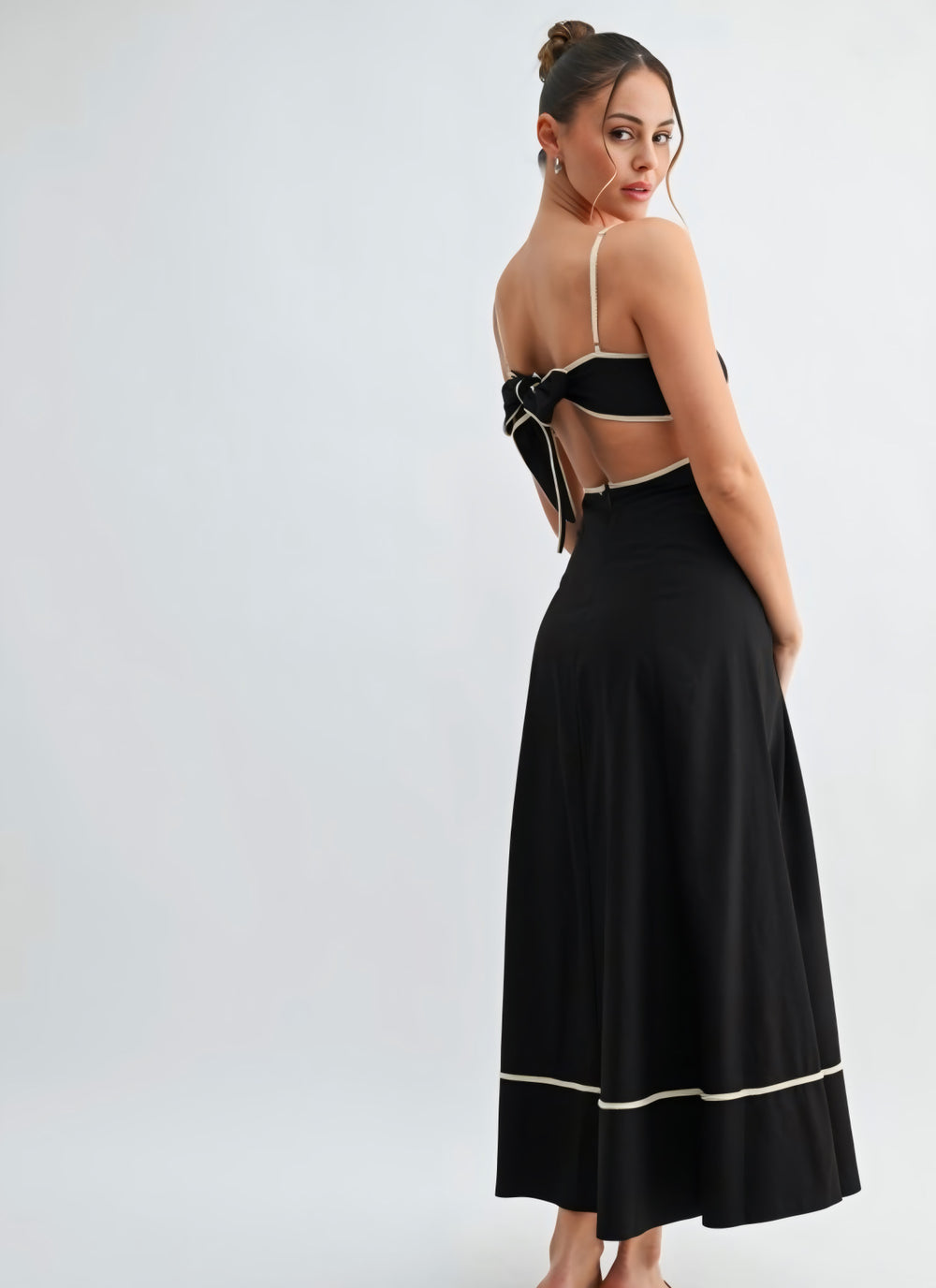 Woman wearing a black dress with cut-out sides on a white background