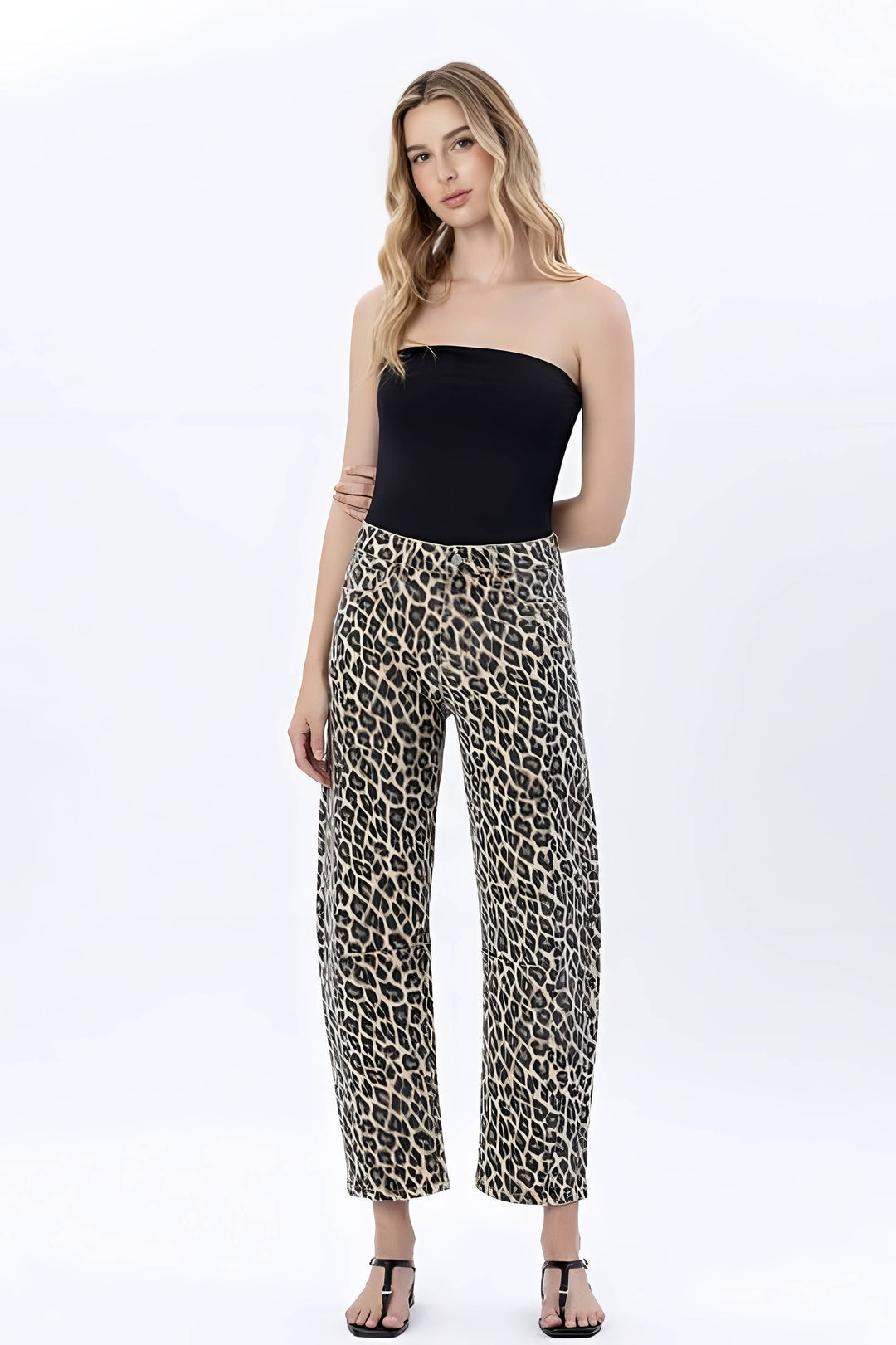 A woman modeling a strapless black tube top and high-waisted leopard-print cropped pants against a plain white studio background.