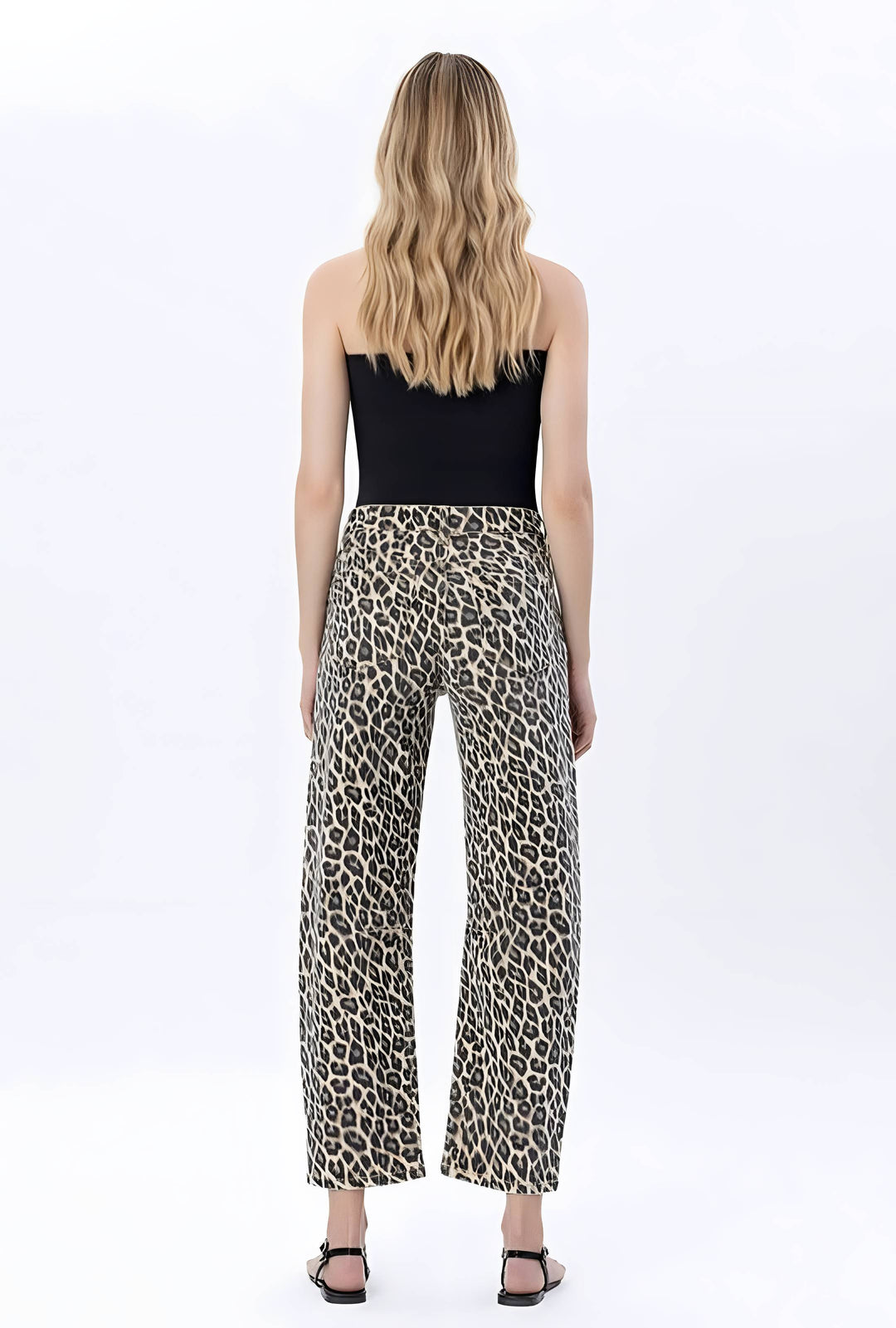 A woman viewed from the back wearing leopard-print wide-leg pants and a black strapless top against a plain white studio background.