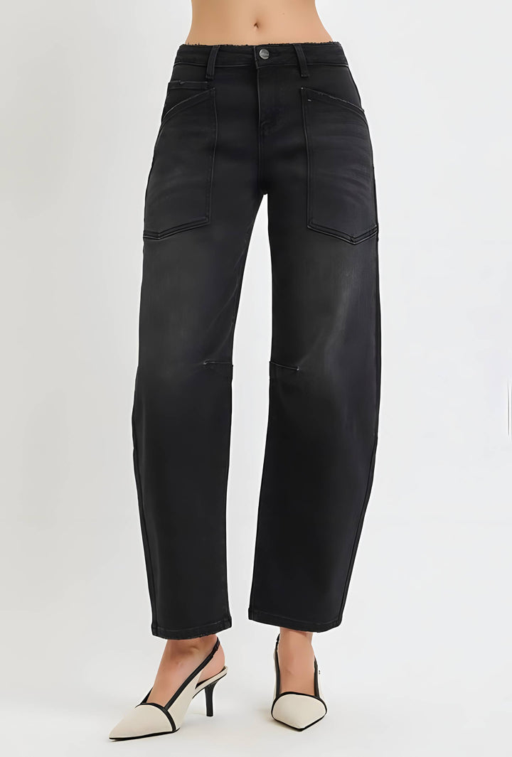 A model is wearing a pair of black wide-leg cropped jeans with a faded wash, paired with beige pointed-toe slingback heels, shown against a plain light gray studio background.