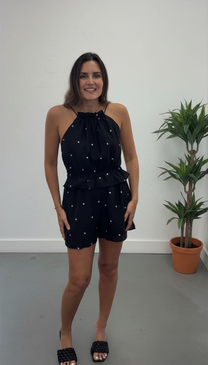 Woman in black dot romper with plant 
