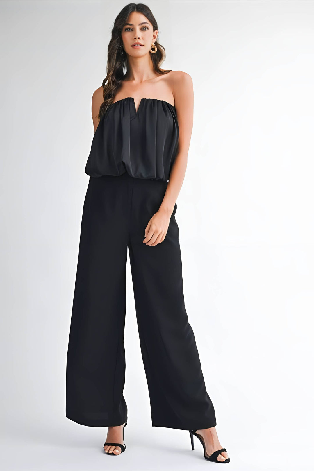 Woman wearing a black strapless jumpsuit on a white background