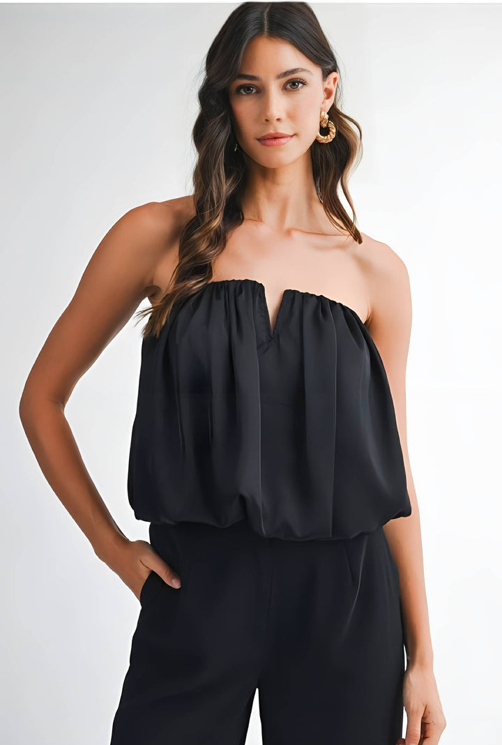 Woman wearing a black strapless top and black pants on a white background