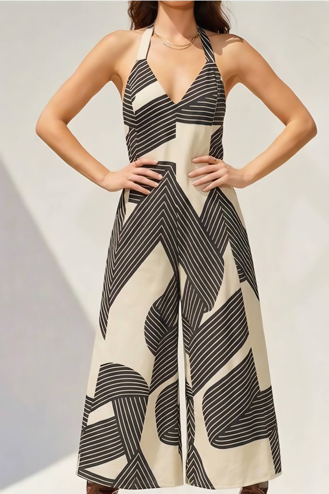 Woman wearing a black and beige patterned jumpsuit on a plain background