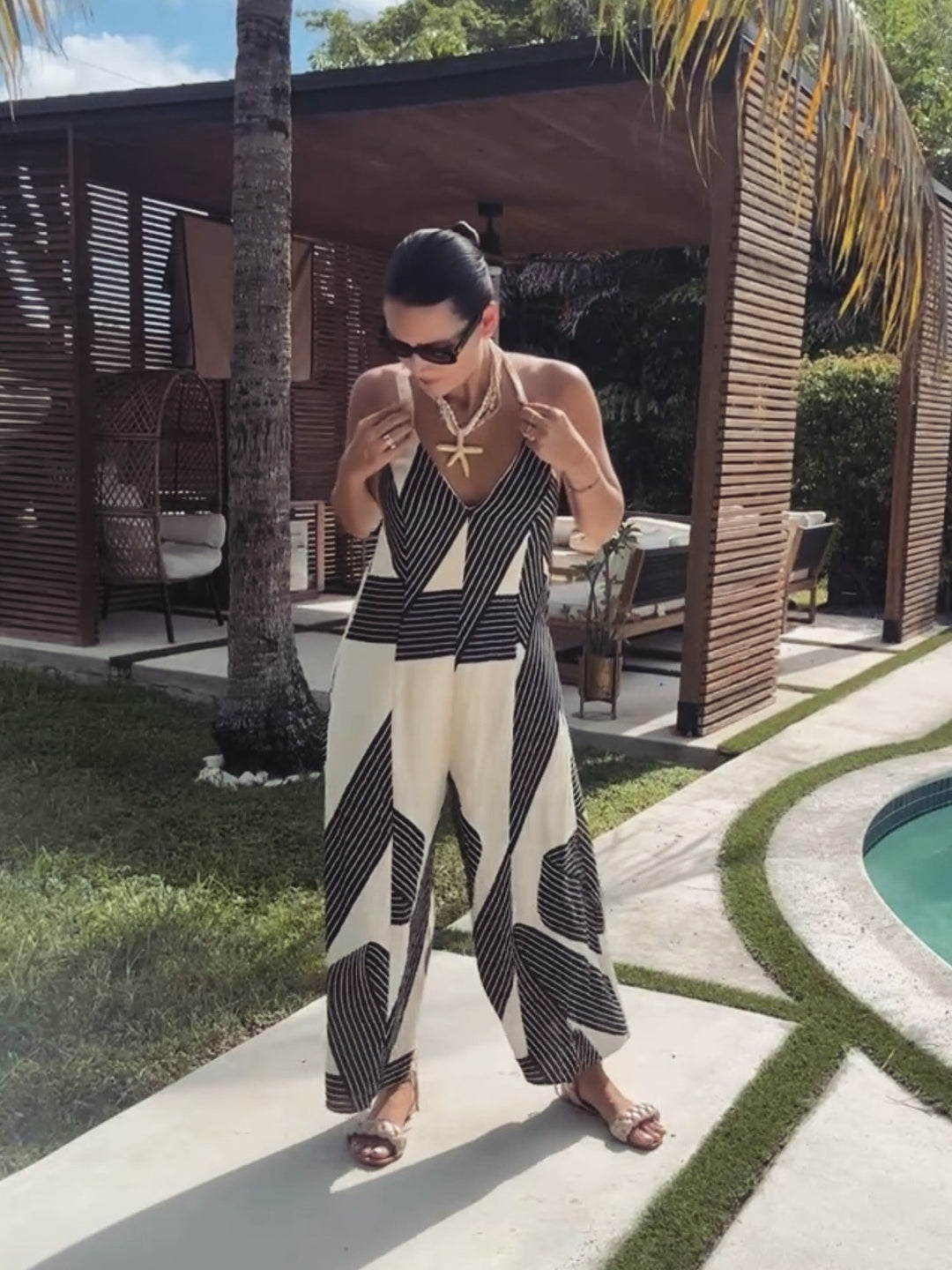 Woman in a black and white patterned outfit standing by a poolside.