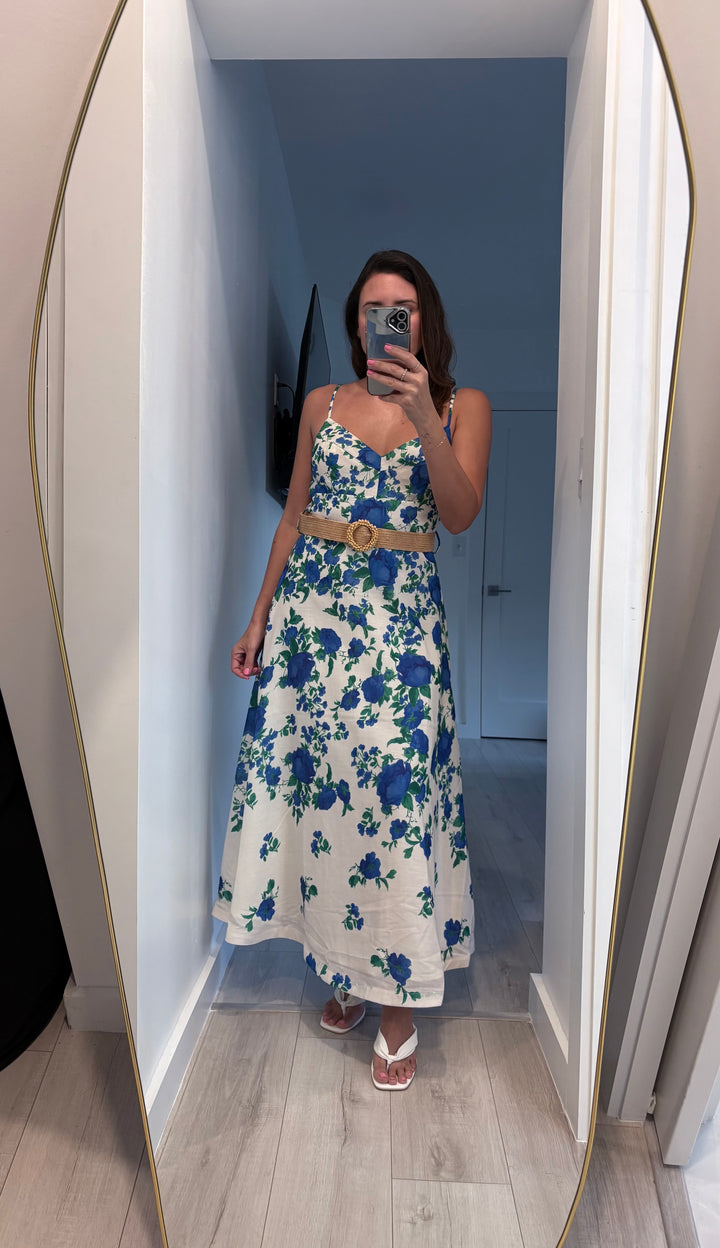 Woman taking a mirror selfie wearing a floral dress with a blue and white color scheme.
