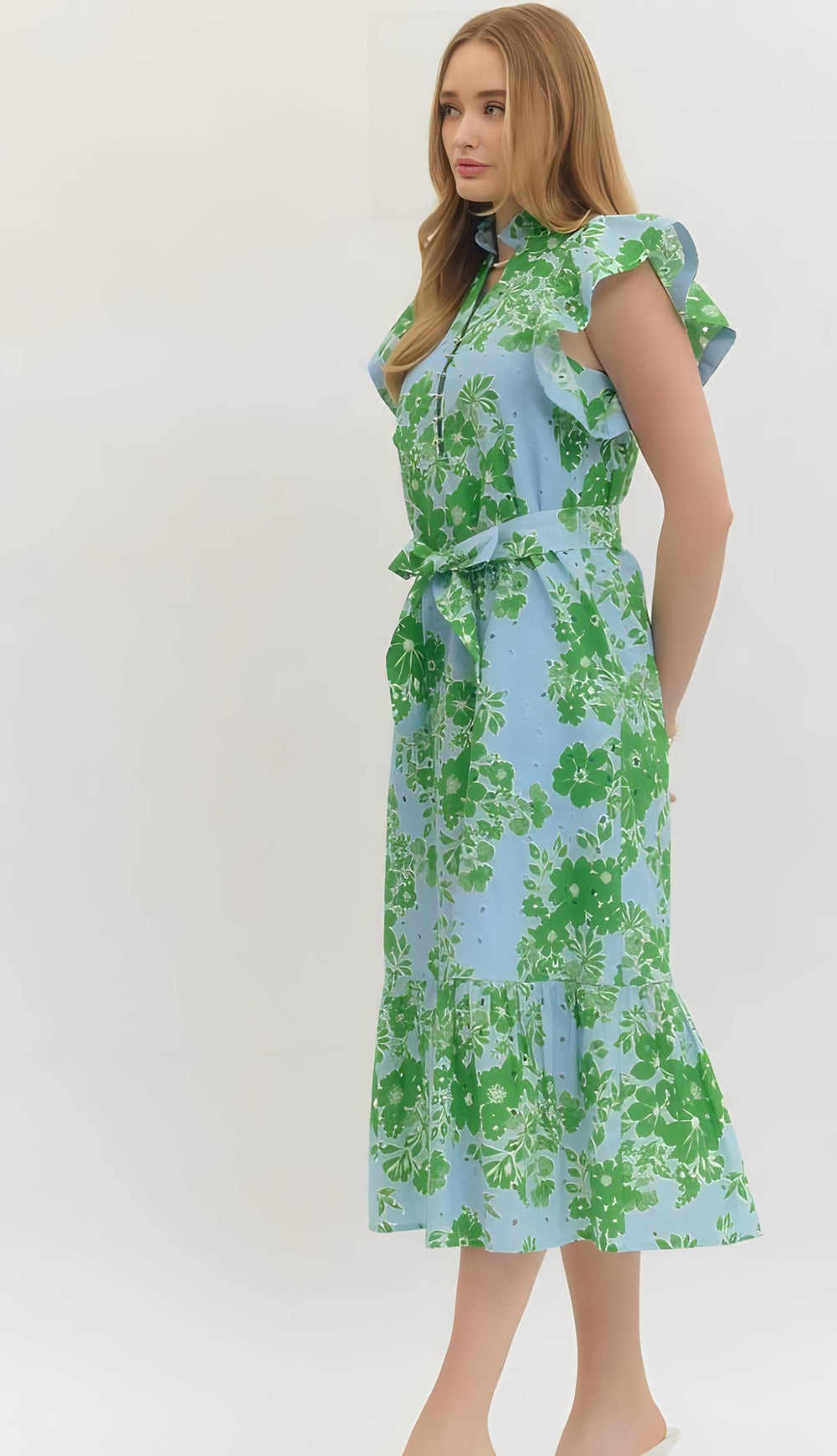 Woman wearing a floral dress with green and blue pattern on a white background