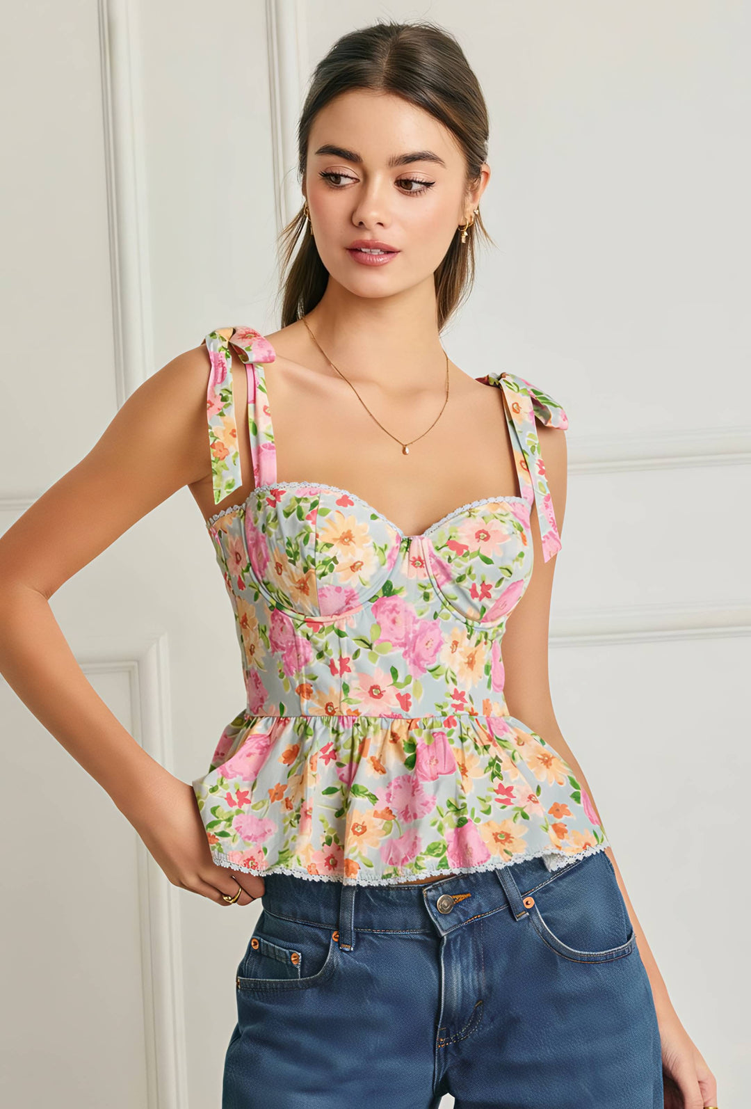Woman wearing a floral top and blue jeans against a white wall