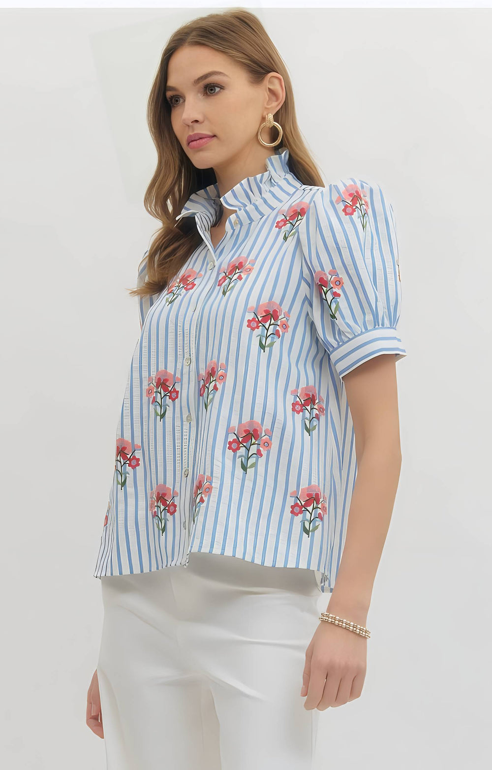 Woman wearing a blue and white striped shirt with floral patterns on a plain background