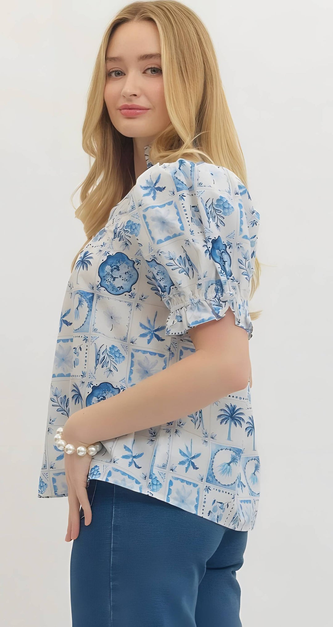 Woman wearing a blue and white patterned blouse with a plain background