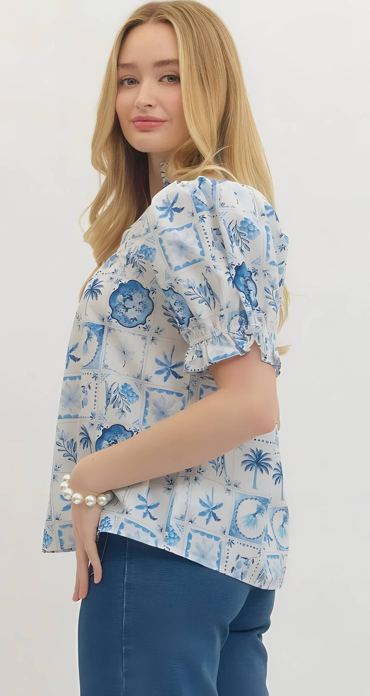 Woman wearing a blue and white patterned blouse with a plain background