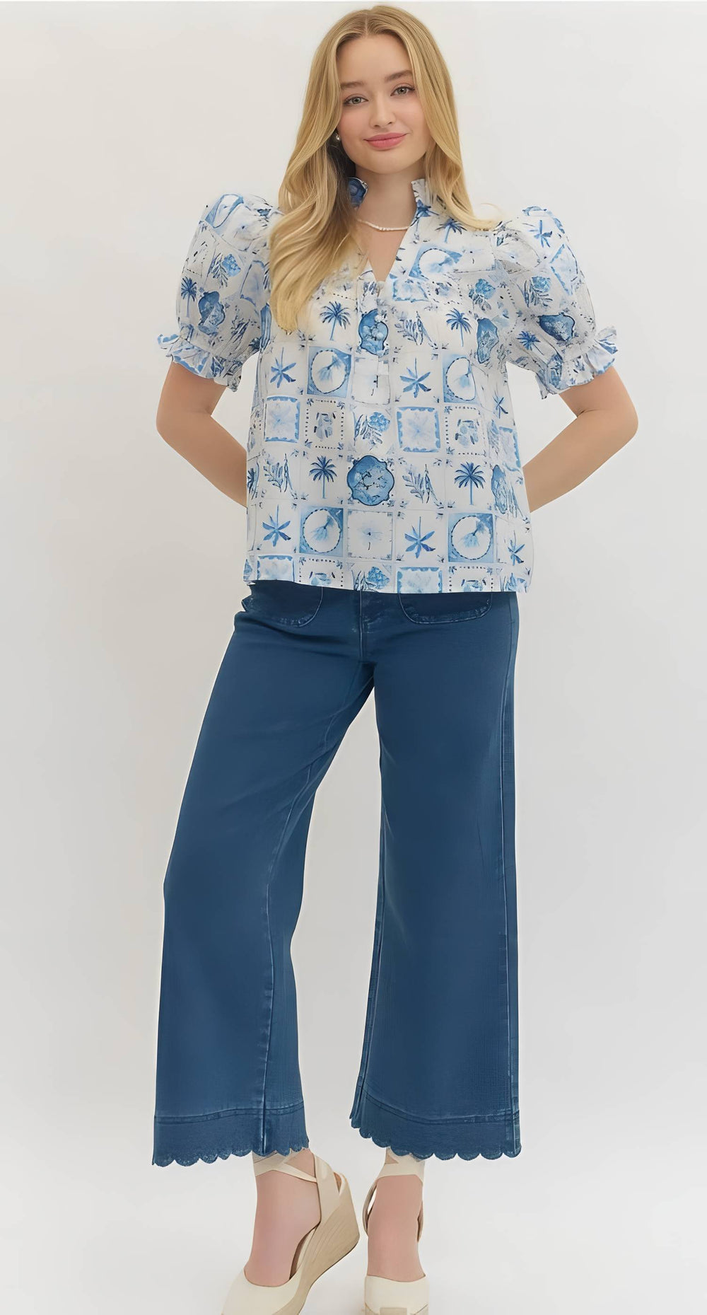 Woman wearing a blue patterned blouse and blue jeans on a white background