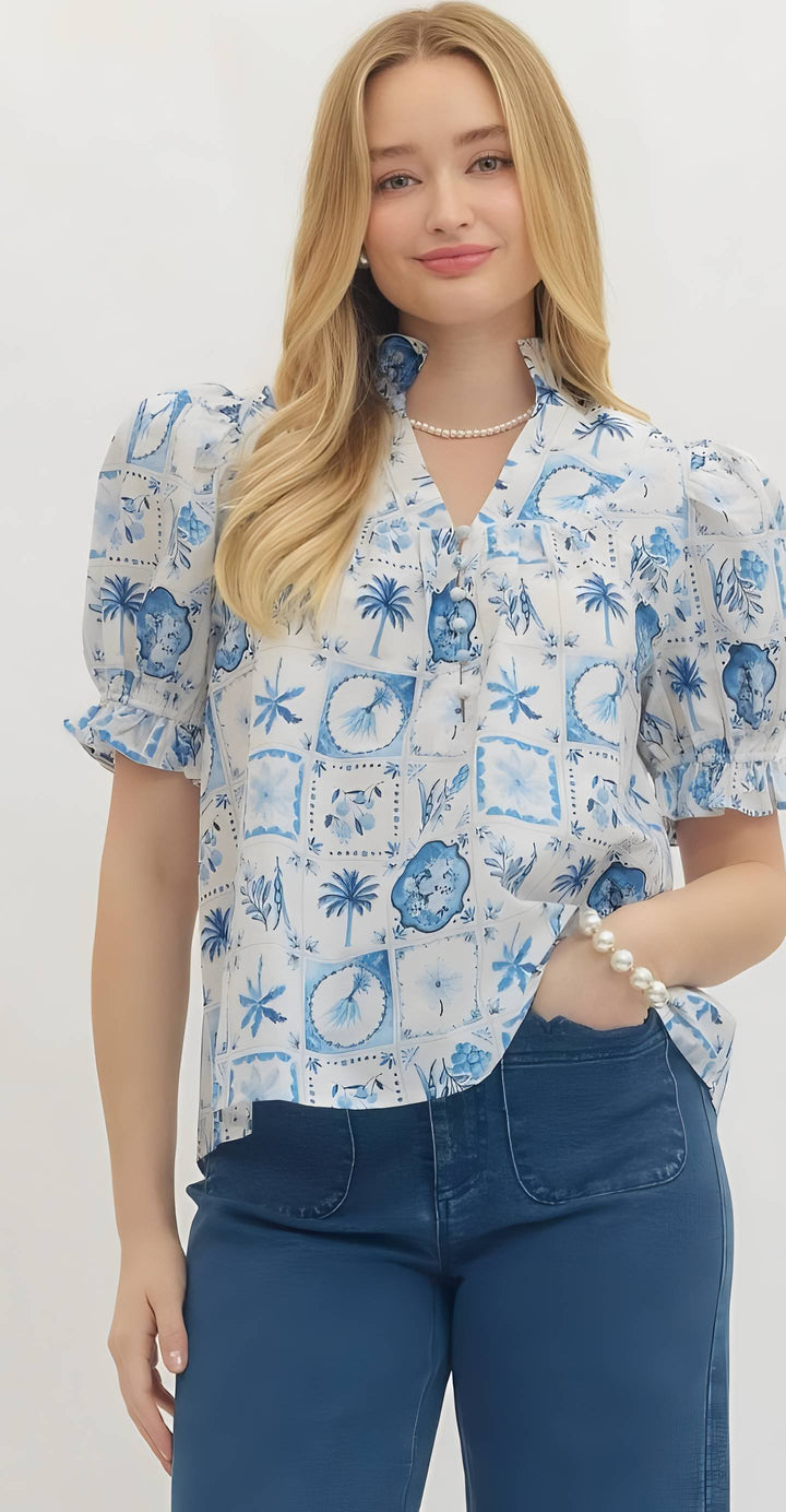 Woman wearing a blue and white patterned blouse with blue jeans on a plain background