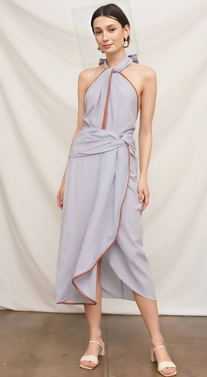 Woman wearing a light blue halter neck dress with orange trim against a white background