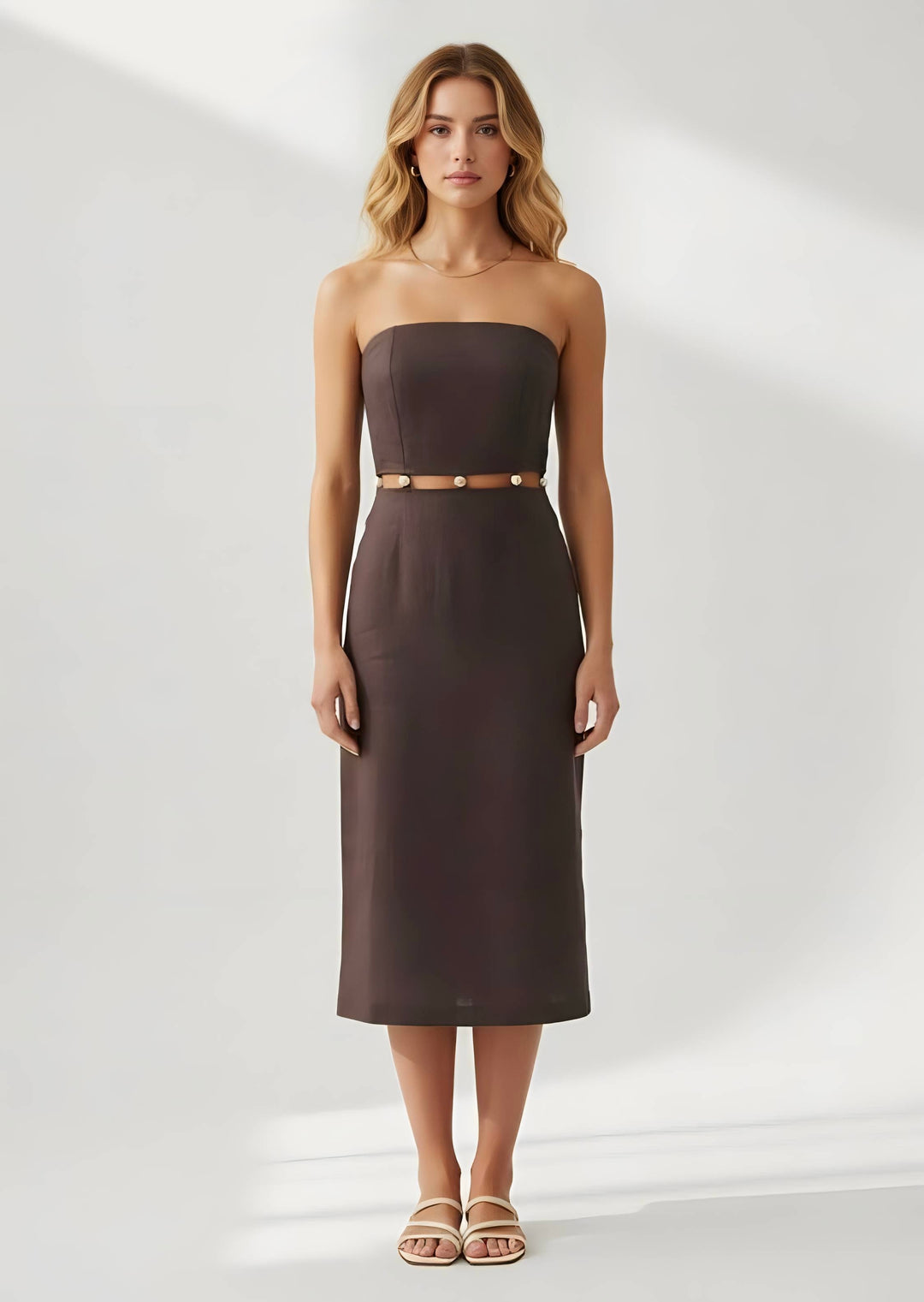 Woman wearing a strapless brown dress with a belt on a white background