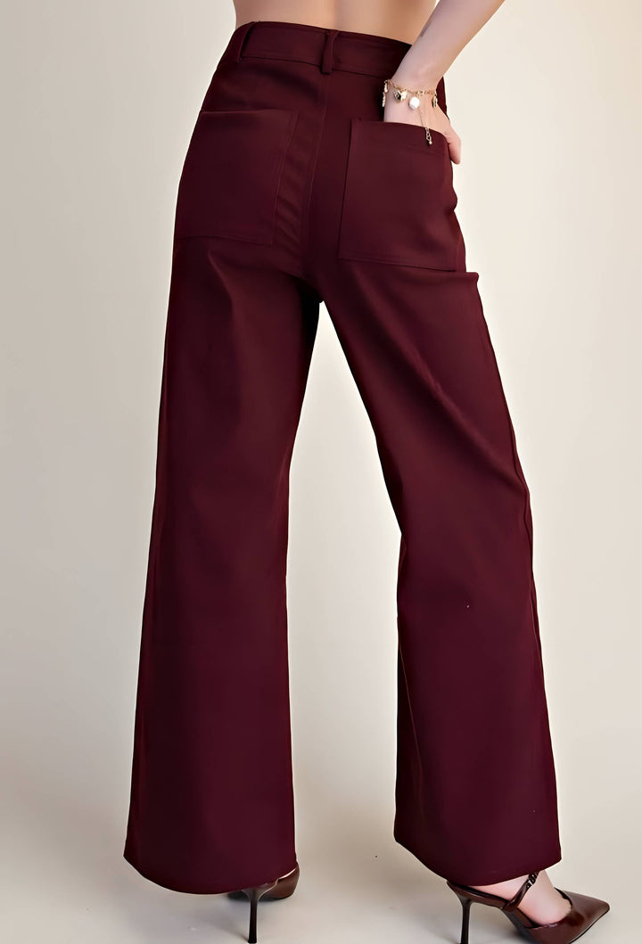 A person wearing high-waisted, wide-leg trousers in a deep burgundy color, shown from the back against a plain beige studio background.