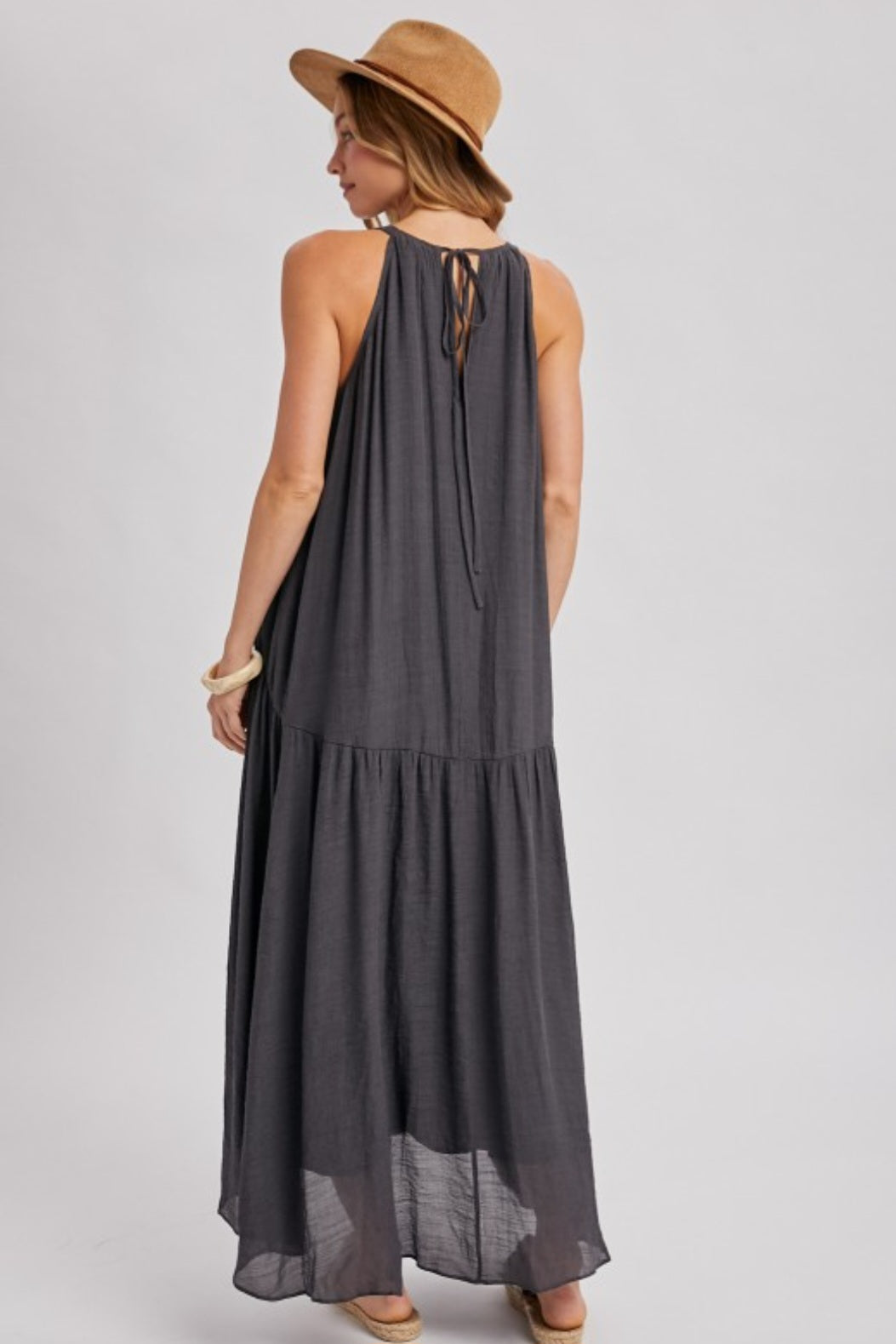 Woman wearing a dark gray halter neck dress with a plain background