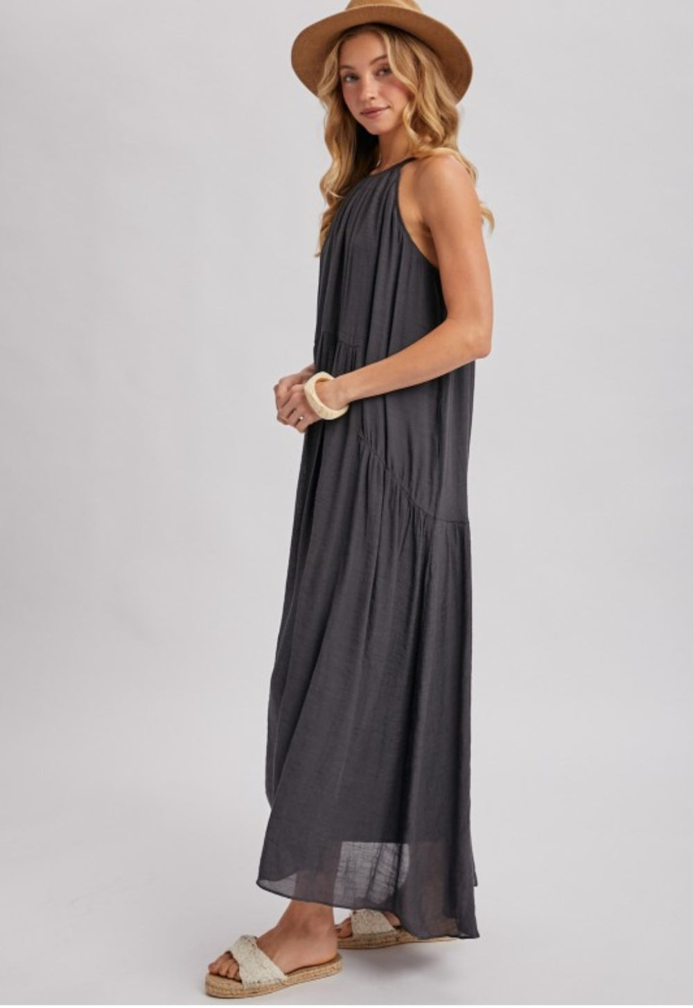 Woman wearing a sleeveless dark gray dress on a white background