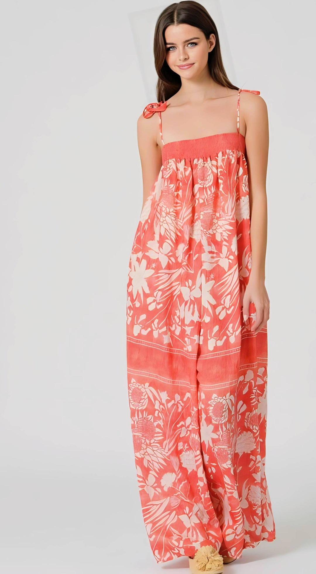 Woman wearing a coral floral jumpsuit on a white background