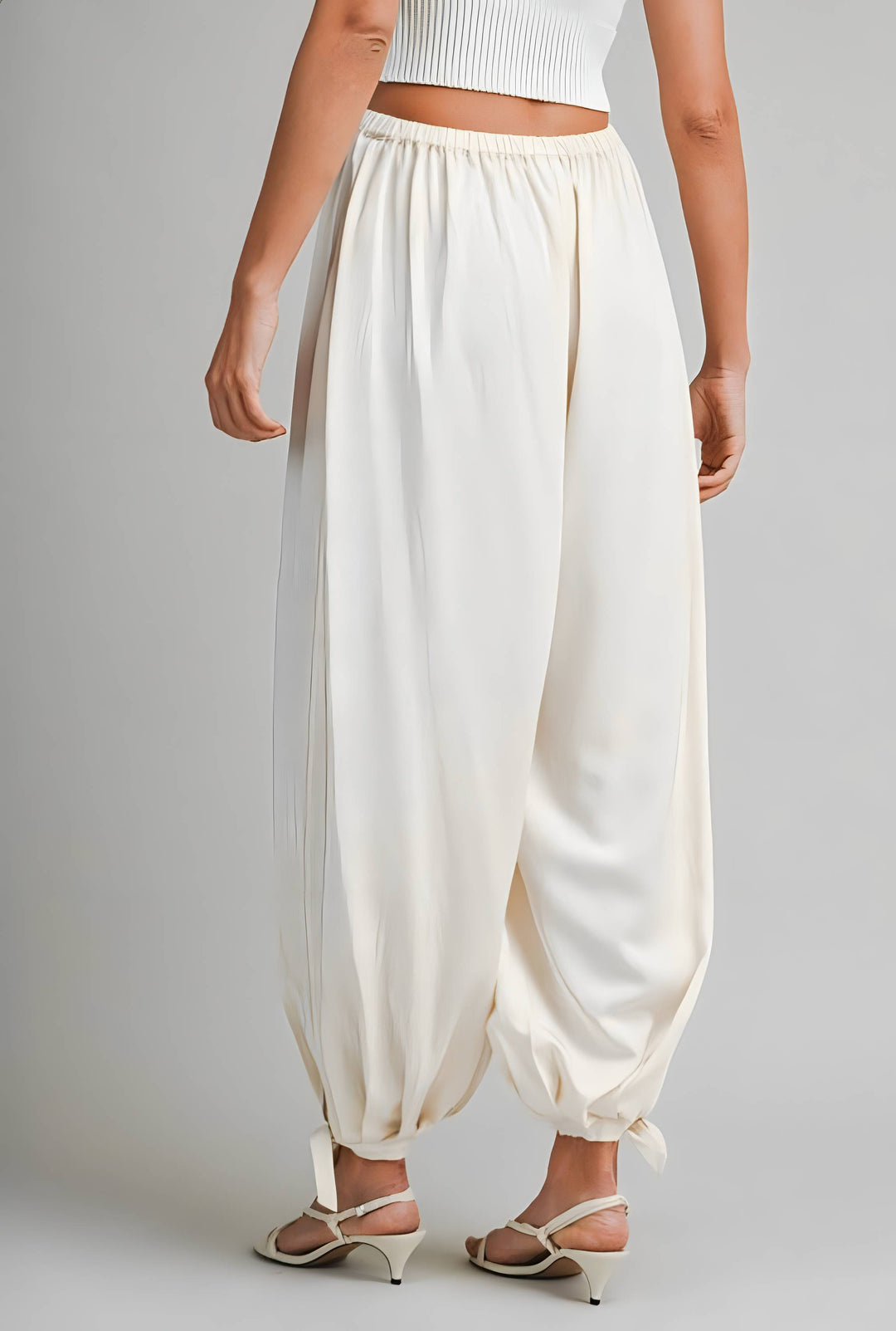 Person wearing cream high-waisted pants on a plain background