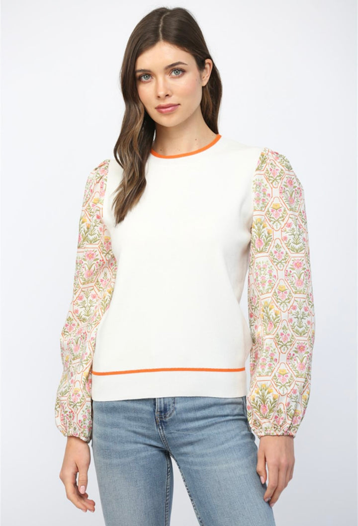 Women’s cream sweater with floral print sleeves and comfortable knit material