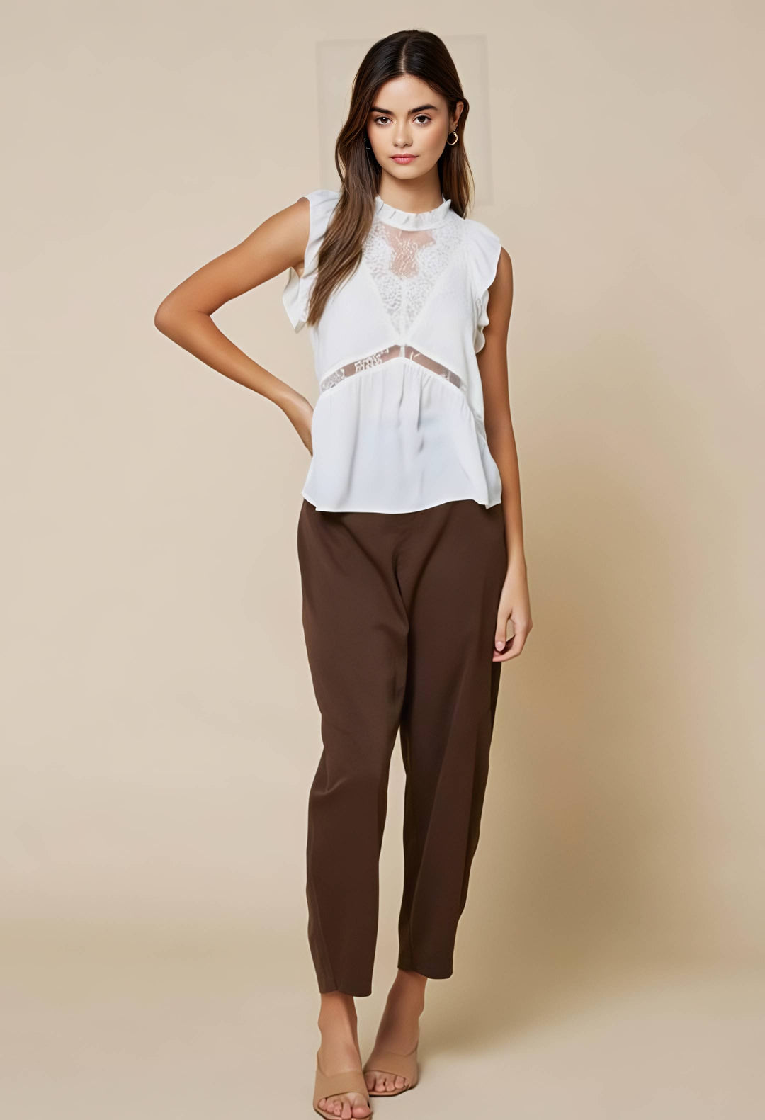 Woman wearing a white blouse and brown pants on a beige background