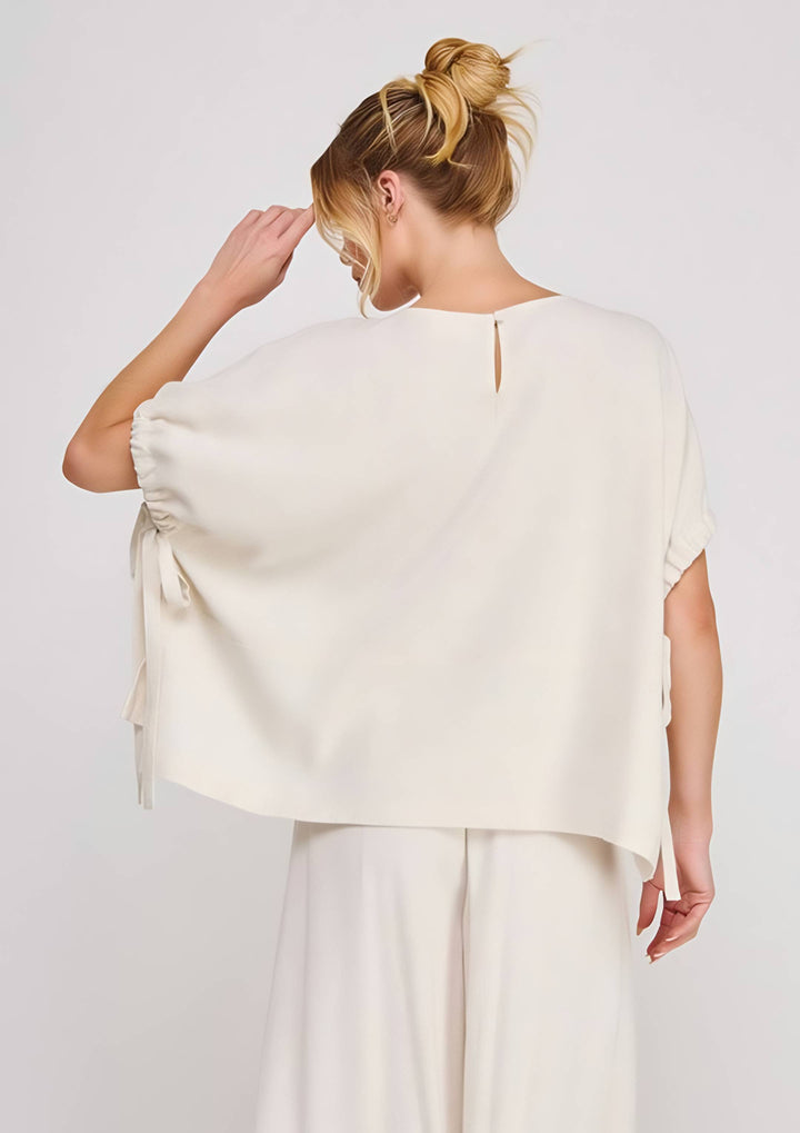 Woman wearing a white top over a plain background