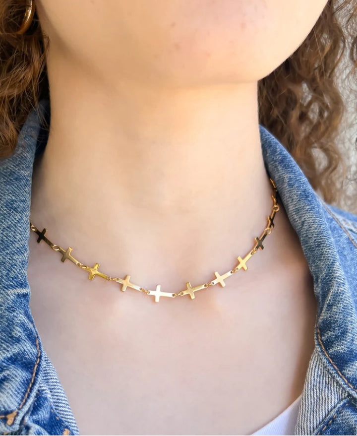 Gold cross necklace worn by a person with a denim jacket