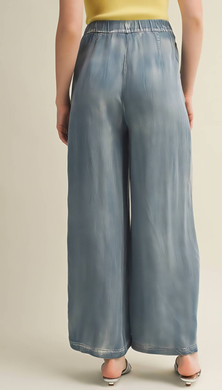 Person wearing light blue wide-leg pants on a beige background