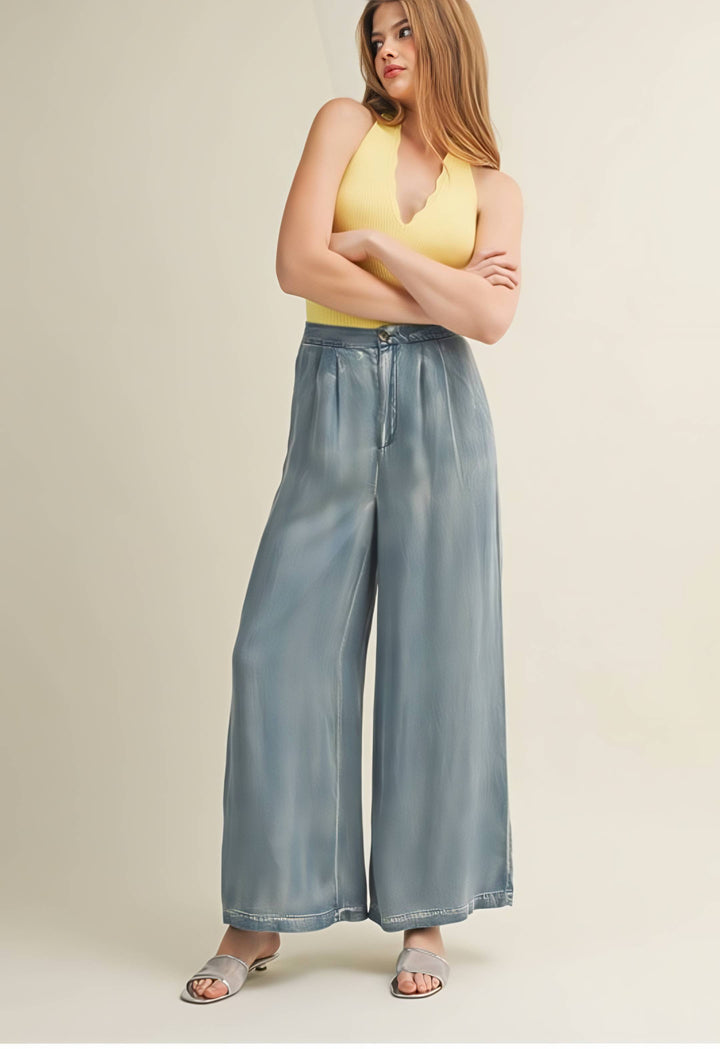 Woman wearing a yellow top and light blue wide-leg jeans on a beige background