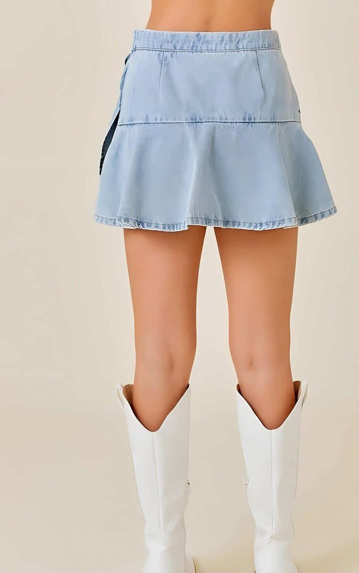 Light blue denim skort worn with white knee-high boots on a beige background