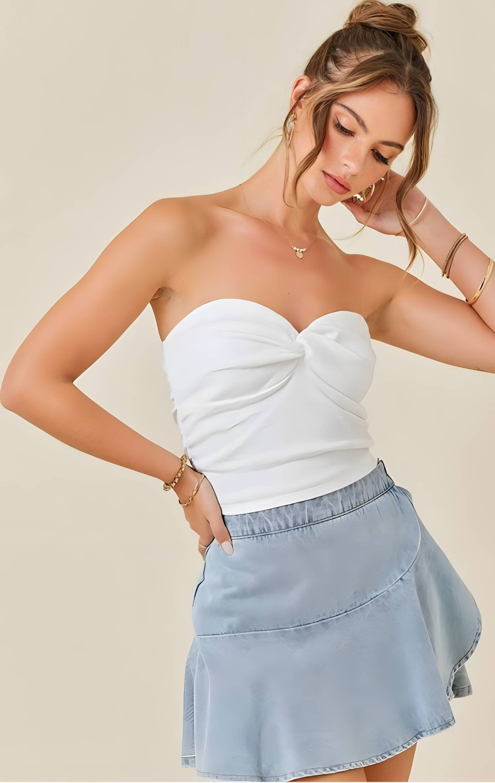 Woman wearing a white strapless top and light blue denim skort on a beige background
