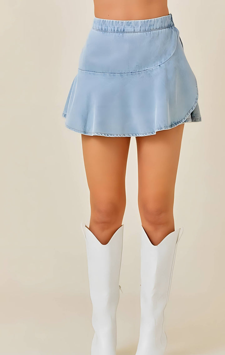 Light blue denim skort worn with white knee-high boots on a beige background