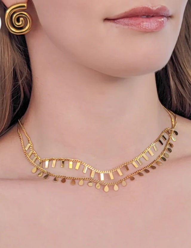 Gold necklace worn by a person with a neutral background