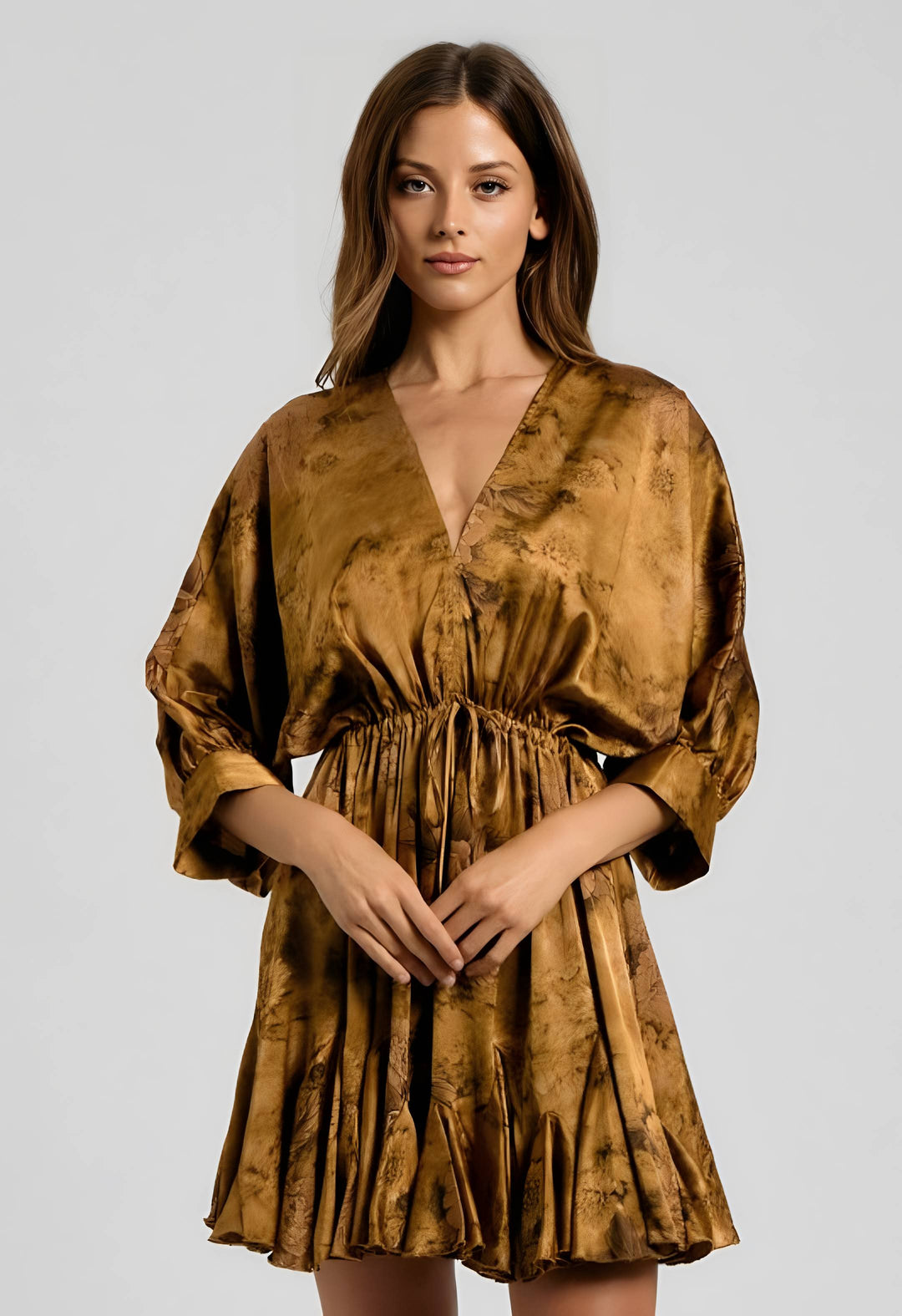 A woman modeling a short, wrap-style dress with three-quarter sleeves in a metallic bronze-gold satin fabric with a subtle tonal pattern, set against a plain light gray studio background.