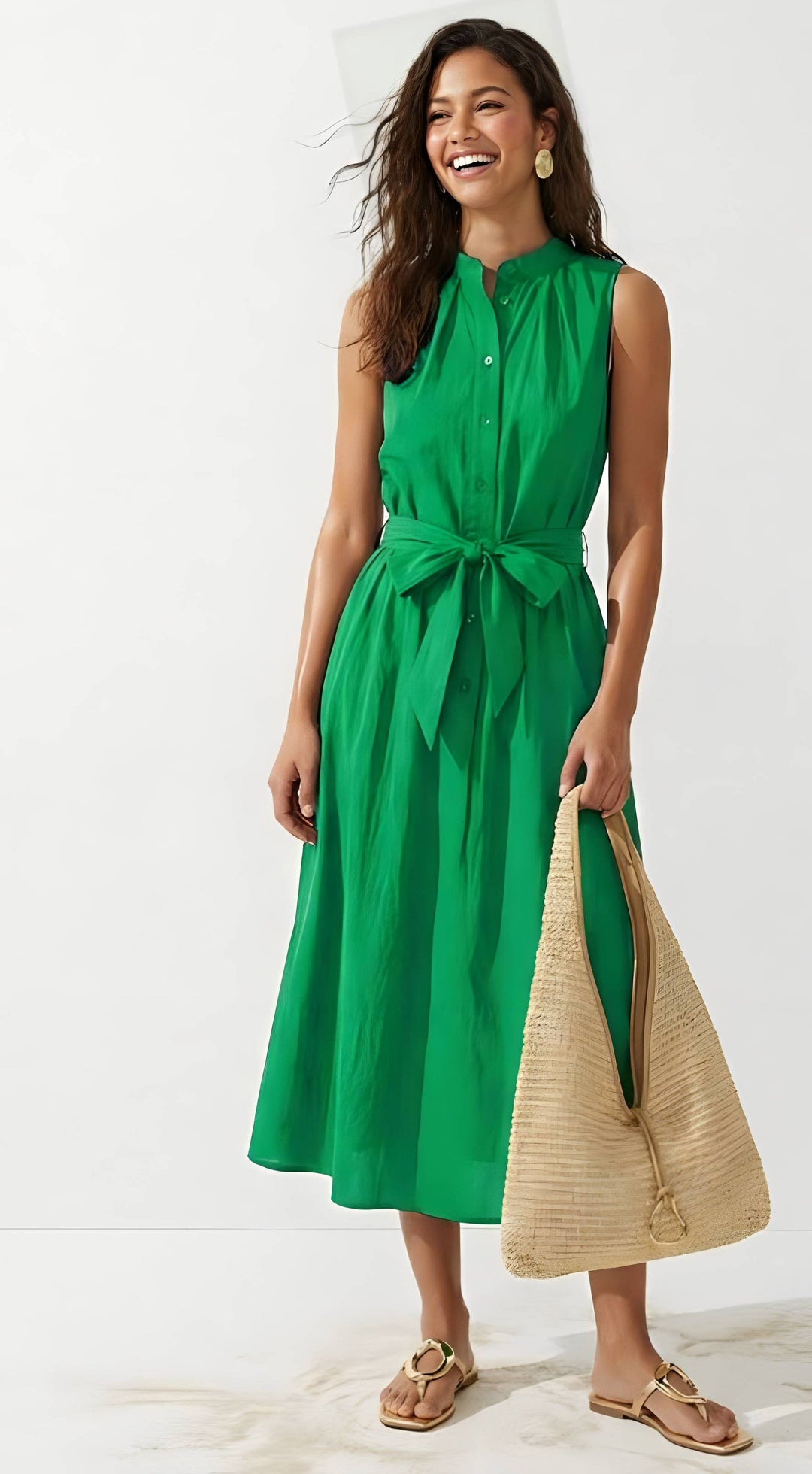 Woman wearing a green dress holding a beige bag on a white background