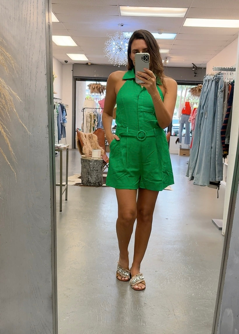 Woman taking a mirror selfie wearing a green outfit in a store.