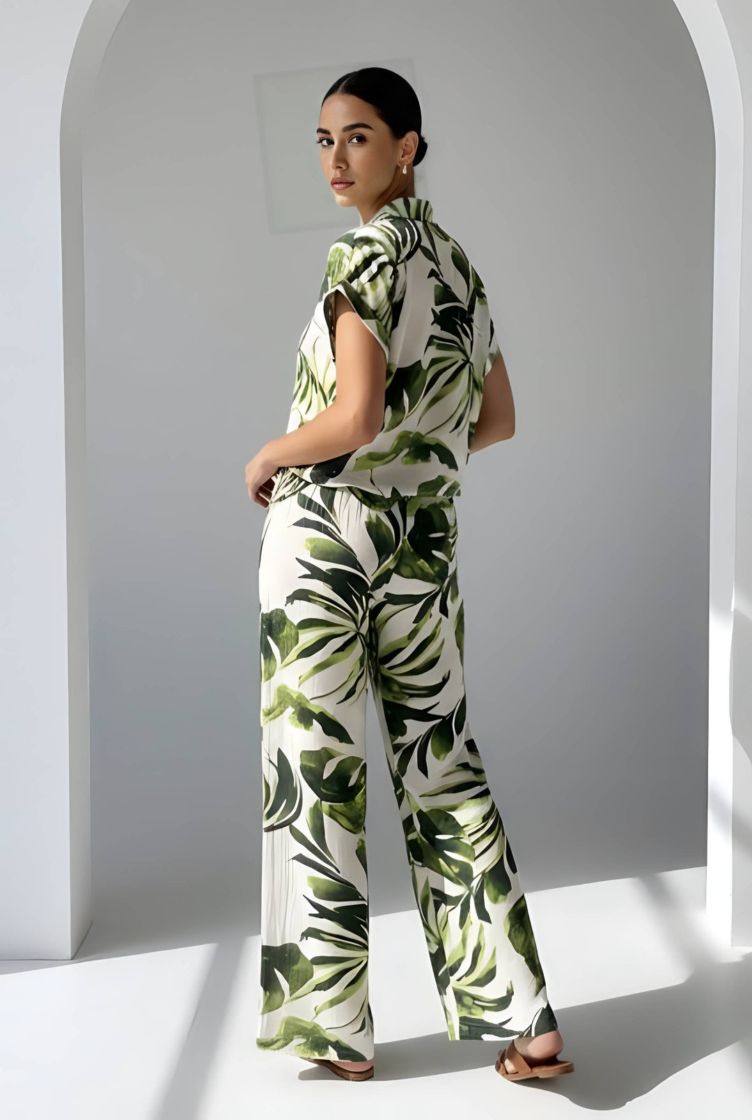 Woman wearing a green and white leaf-patterned outfit standing against a white background.