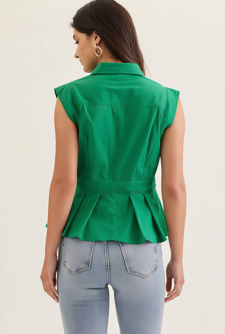 Woman wearing a green sleeveless peplum top and light blue jeans on a beige background