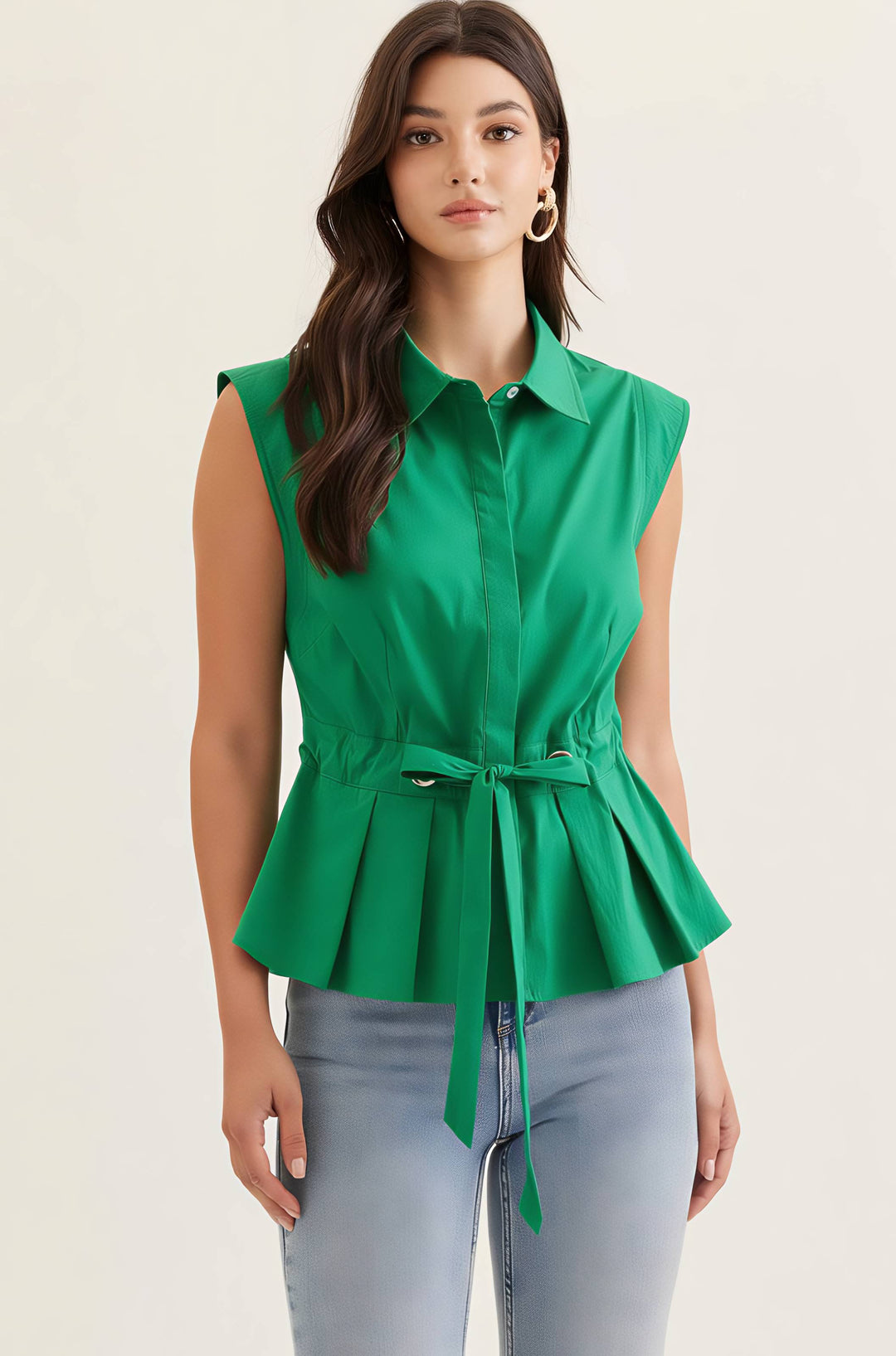 Woman wearing a green sleeveless peplum top with a belt against a beige background