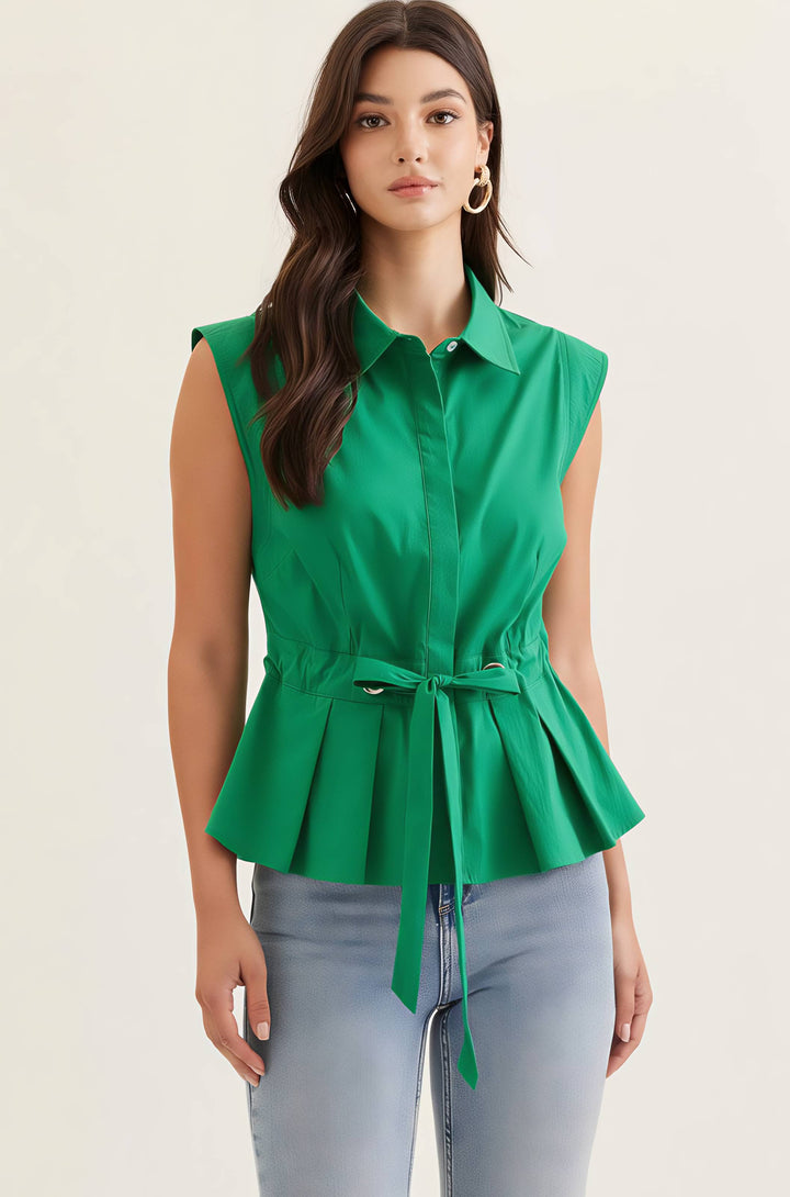 Woman wearing a green sleeveless peplum top with a belt against a beige background