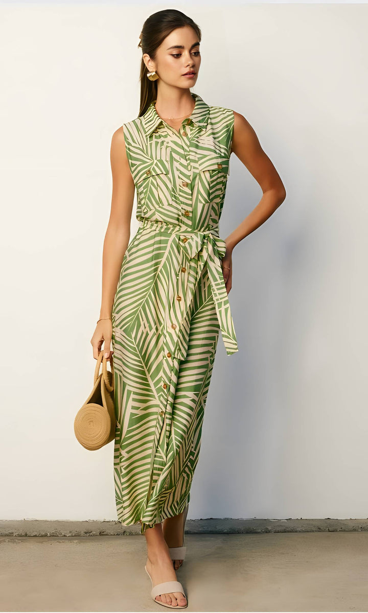 Woman wearing a green patterned dress holding a round bag against a white background