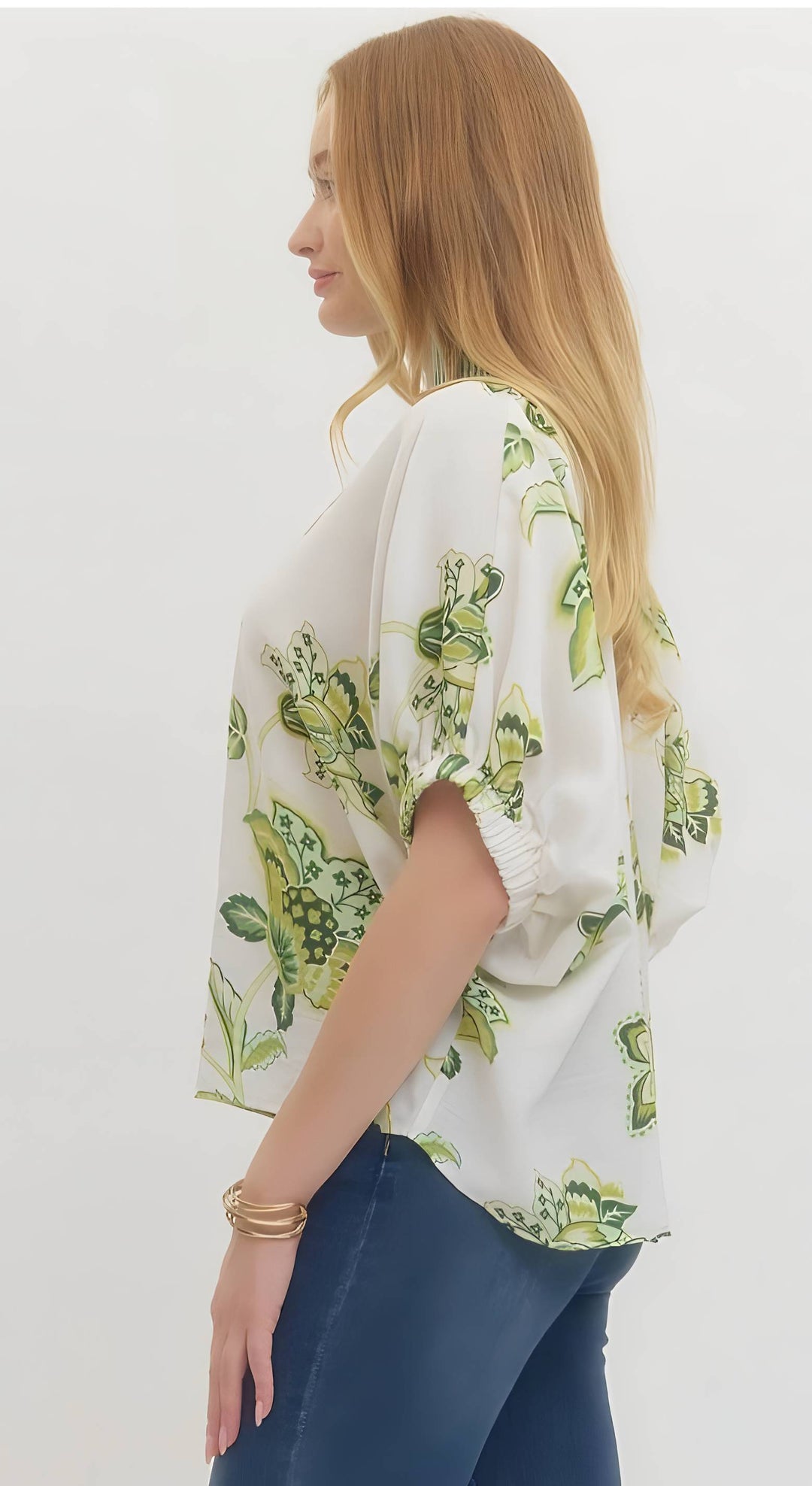 Woman wearing a white blouse with green floral pattern on a plain background